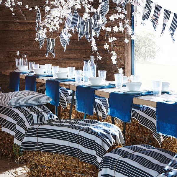 White-and-dark blue striped METTALISE metre fabric is shown in a barn table setting used as hay bail covers and flag decor.