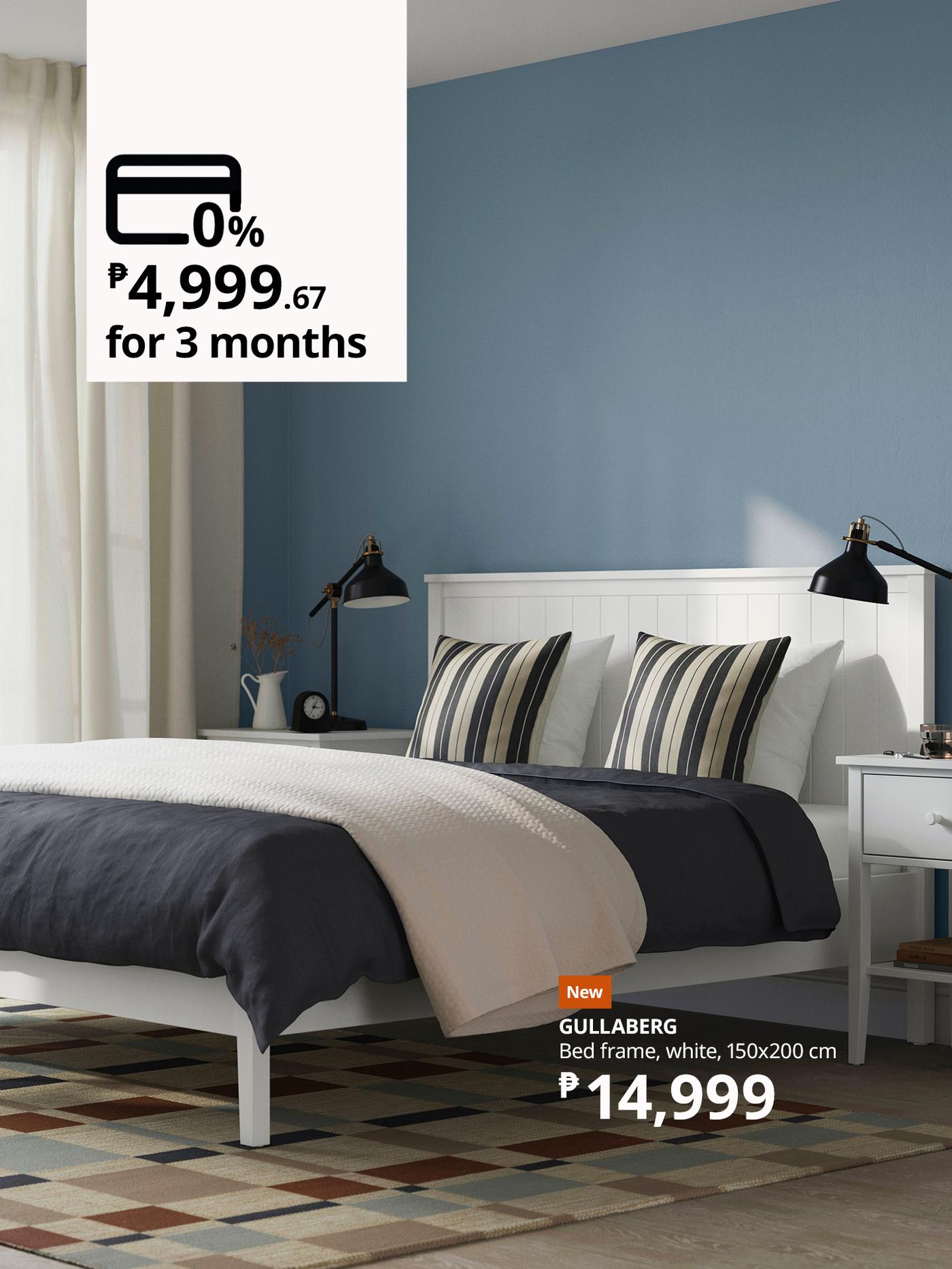 White bed frame with striped pillows, a dark gray blanket, two black lamps, and a nightstand in a modern bedroom. Price tag and installment details displayed in the image.