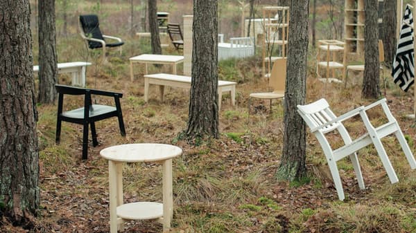 White, black, and light wooden tables and chairs scattered throughout a forest, one source of our renewable materials.