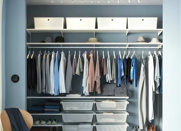 White BOAXEL wardrobe combination filled with clothes, hangers and KUGGIS boxes in bedroom.