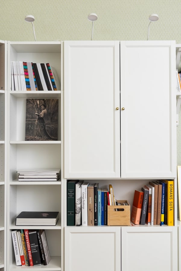 White bookshelf detail with books, storage boxes, and minimalist decor