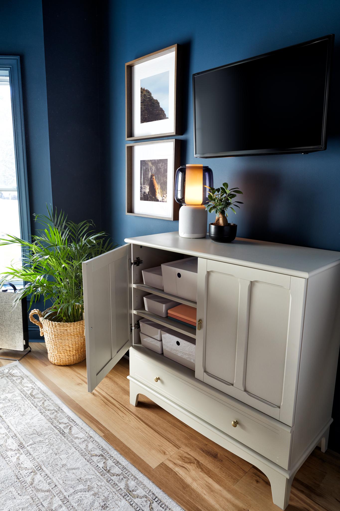 White cabinets under a monitor and framed photos
