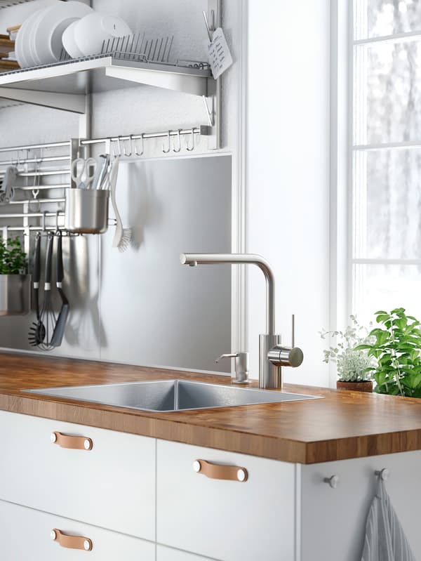 White cabinets with white drawer fronts and ÖSTERNÄS leather handles below a wooden worktop with a sink and mixer tap.
