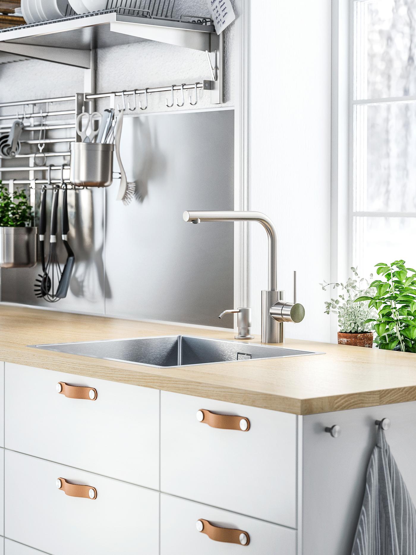 White cabinets with white drawer fronts and ÖSTERNÄS leather handles below a wooden worktop with a sink and mixer tap.