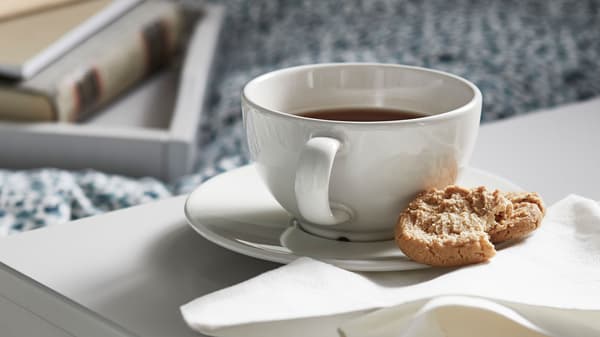 White coffee cup with a half-eaten cake on the coffee tray.