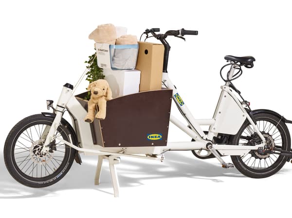 White e-cargo bike loaded with a box, a cuddly toy, and a basket