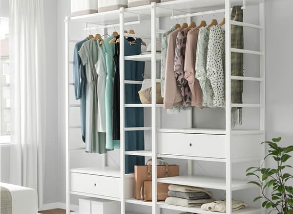 White ELVARLI wardrobe combination filled with clothes, hangers and boxes in bedroom.