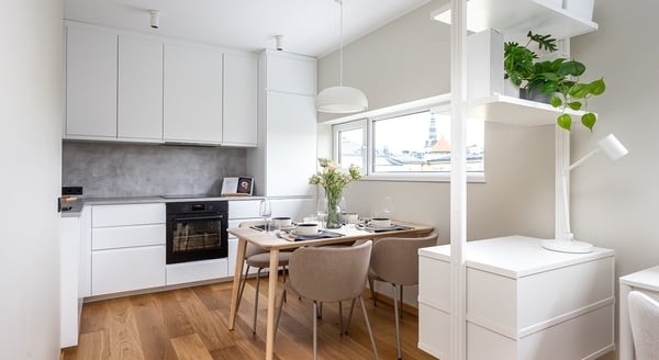 White modern kitchen with dining table and built-in cabinets.