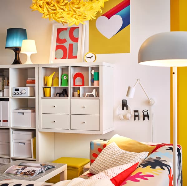 White NYMÅNE floor lamp and yellow GRIMSÅS pendant lamp illuminating the living room.