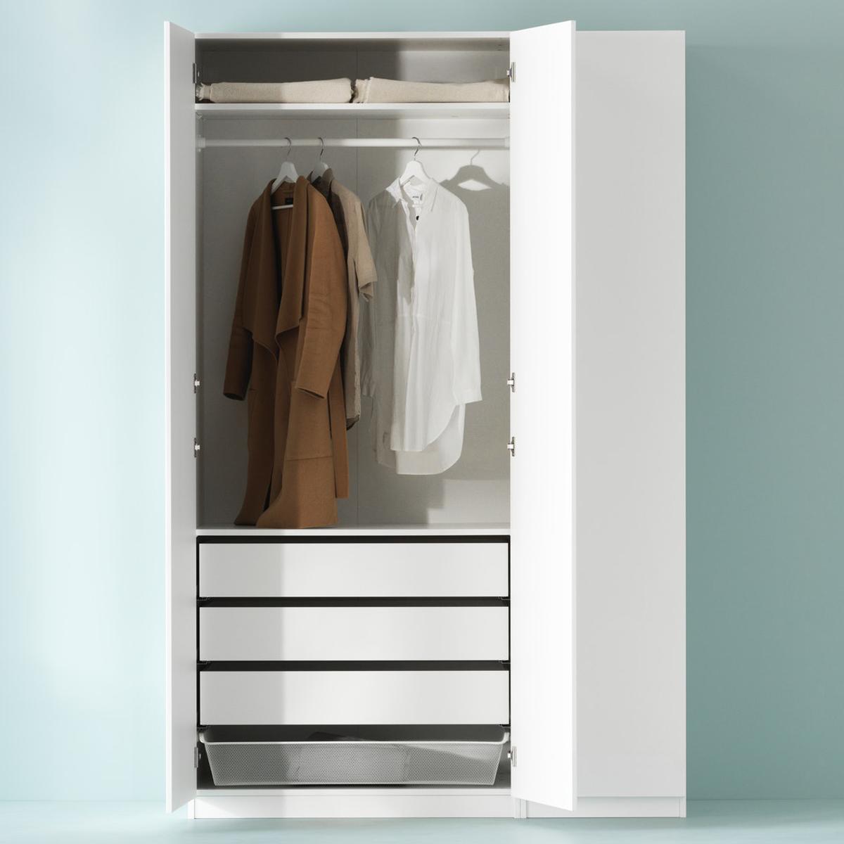 White PAX wardrobe against a light-green wall, two hinged doors open, shirts hang on a rail above drawers and a mesh basket.