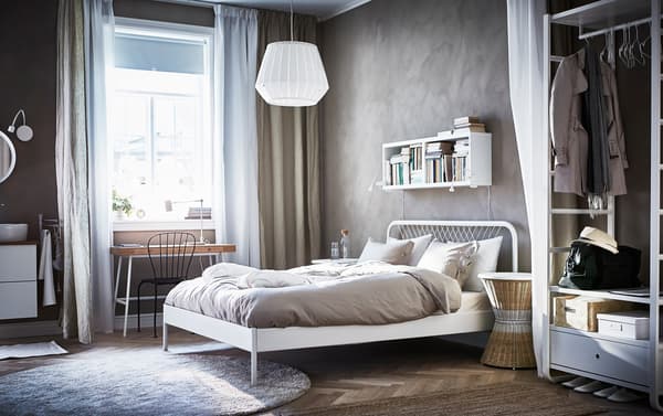 White Scandinavian styled IKEA NESTTUN wired bedframe in a crisp room with beige walls and an open air wardrobe.