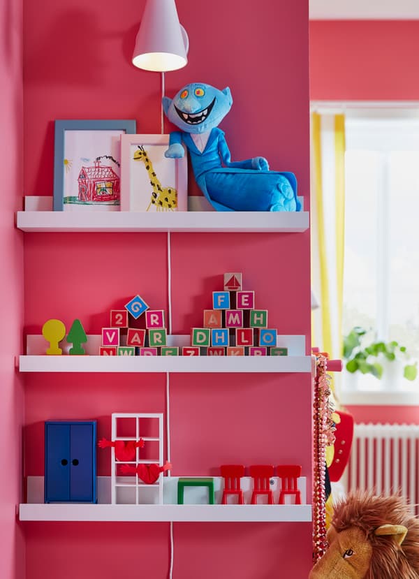 White shelves on a pink children's room wall