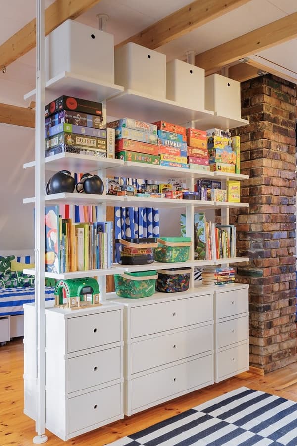 White shelving unit with books, toys and board games in kids room