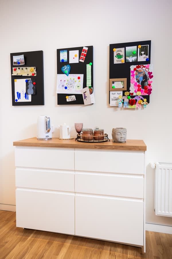White sideboard with drawers and wall décor above; crockery and kitchen accessories placed neatly on top.