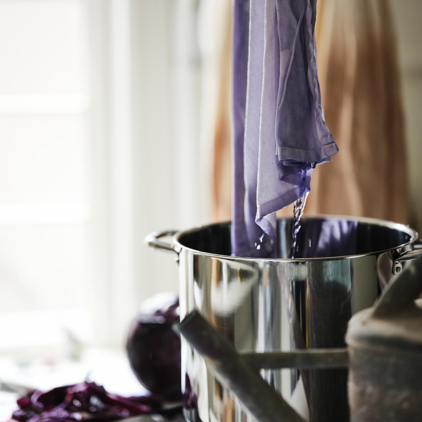 White SILVERLÖNN fabric, lowered into a dark liquid in an IKEA 365+ stockpot on a white TILLREDA portable induction hob.
