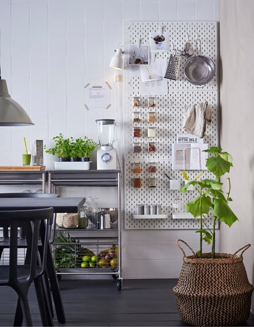 White SKÅDIS pegboards attached to a kitchen wall next to a worktop with accessories to hold recipes and smoothie ingredients  