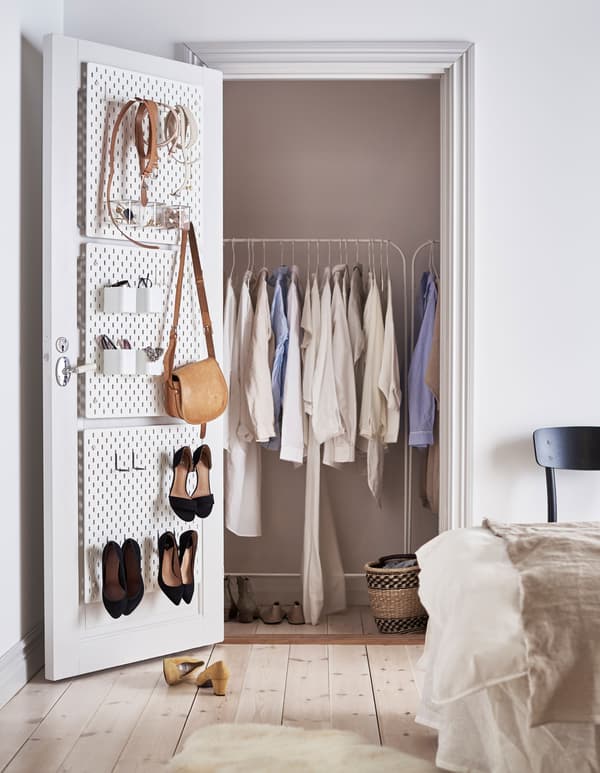 White SKÅDIS pegboards attached to the inside of a closet door to organise accessories and shoes