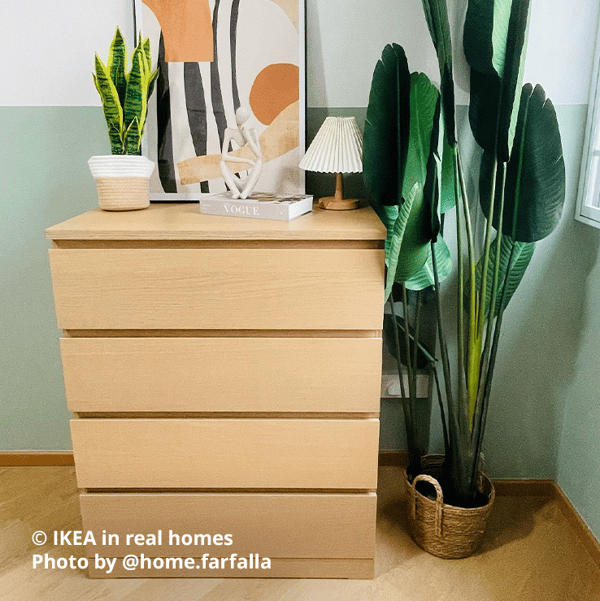 White stain oak effect MALM chest of 4 drawers in the bedroom next to a large potted plant, with various decorative items and table lamp as well as a large photo frame with a poster on top of the drawers. Photo by instagrammer @home.farfalla for IKEA in real homes.