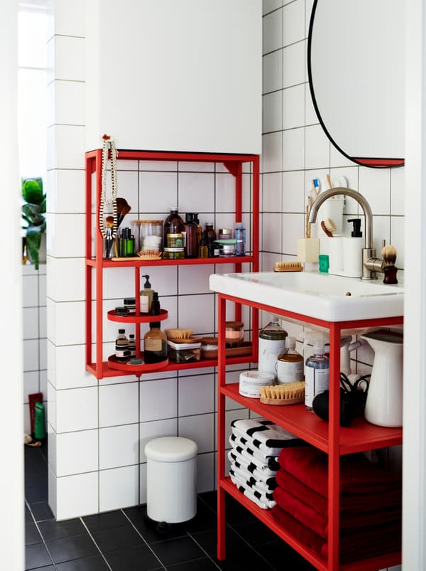 White-tiled bathroom furnished with a mix of red and white ENHET modules, holding decorations and accessories.