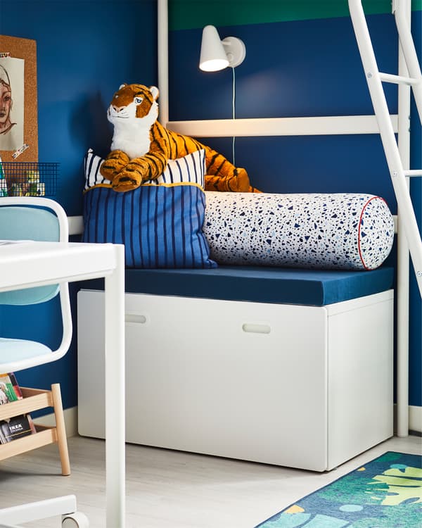 White toy storage placed under a white loft bed where you can sit thanks to comfortable cushions on top.