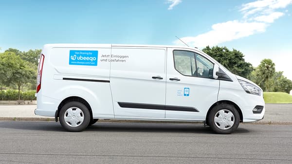 White van with the label “Log in and drive off now” from Ubeeqo Carsharing, parked on a street.








