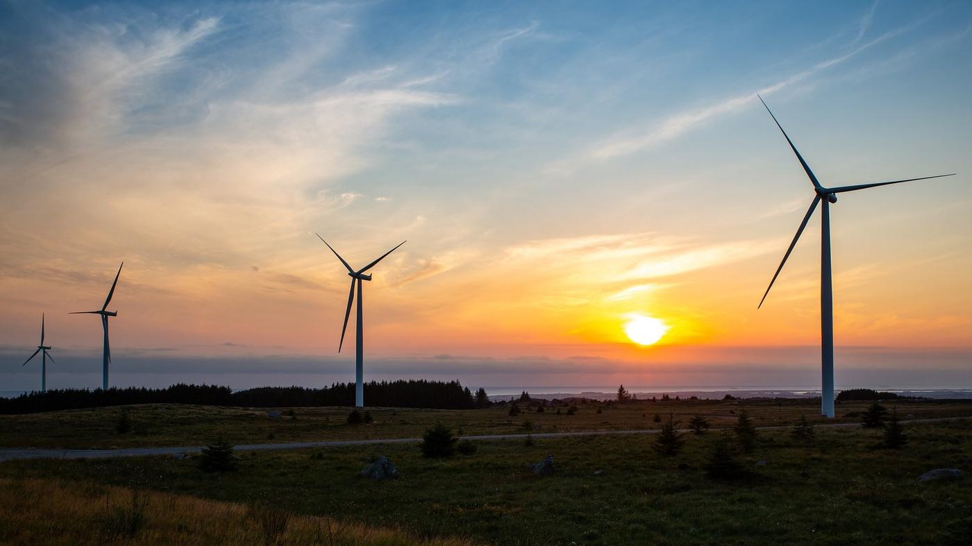 Wiatraki produkujące energie na tle zachodzącego słońca.