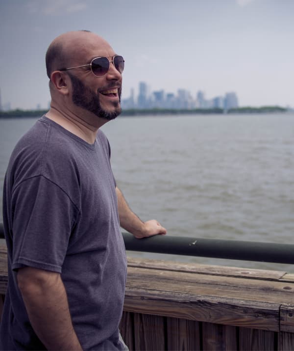 William ยืนมองน้ำที่มีพื้นหลังเป็นเส้นขอบฟ้าของเมือง