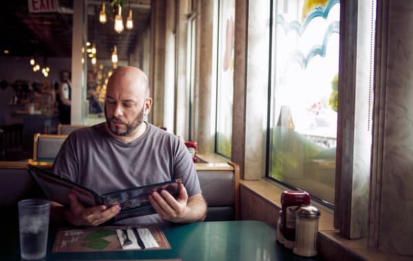 William นั่งอยู่ในร้านอาหารอ่านเมนูอยู่