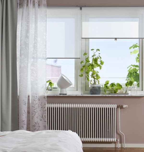 Windows in a bedroom with blinds and curtains partially open.