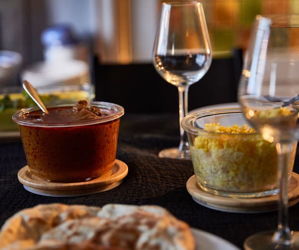 Wine glasses and IKEA 365+ glass containers with bamboo lids filled with different foods.
