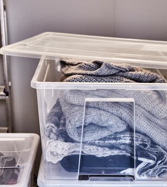 Winter clothing is stored in stackable, clear plastic boxes.