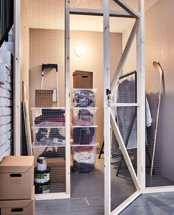 Winter clothing stored in an attic space in transparent, stackable plastic boxes, cardboard boxes and a clothing rail.