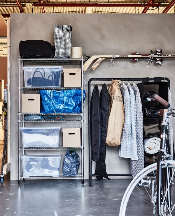 Winter sports gear and clothing are stored in plastic and paper boxes, sturdy plastic bags, and on racks in a garage.