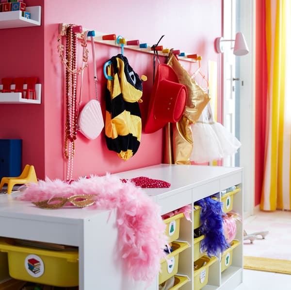Wit FLISAT knoppenrek boven een STUVA combinatie, om mutsen, verkleedkleren en namaakjuwelen aan te hangen.