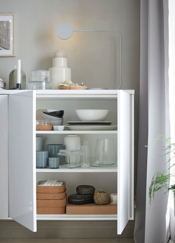 Witte IKEA METOD kastelementen, met deuren in hoogglans wit, gebruikt om servies in op te bergen.