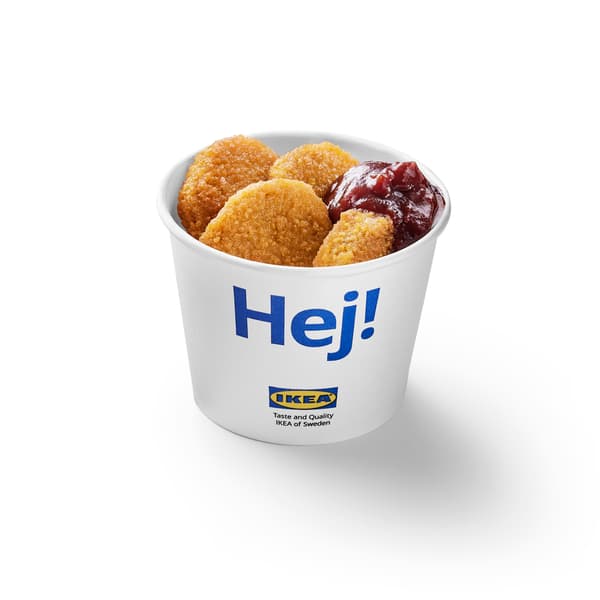 Witte kartonnen IKEA-beker met blauwe "Hej!"-opdruk, gevuld met vier gepaneerde kipnuggets en een portie rode saus.