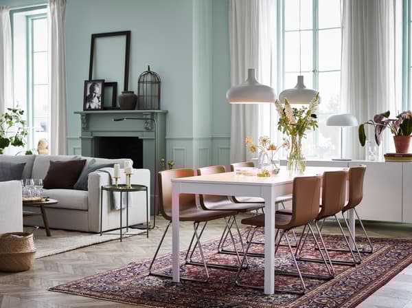 Witte uitschuifbare IKEA EKEDALEN tafel en BERNHARD stoelen in bruin leder in een moderne open eetruimte.