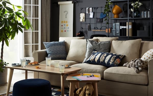 Wohnzimmer mit Sofa und Couchtisch. Hier werden gerade Origamifiguren gefaltet und Snacks und Getränke genossen.