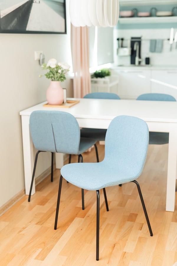 Woman arranging glass bottles on dining table in a bright modern kitchen
