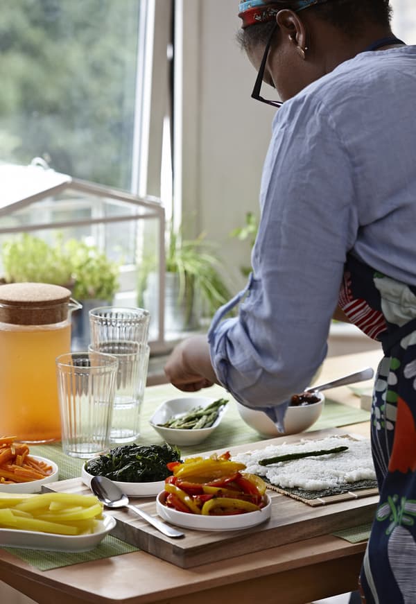 Woman bent over a kitchen counter with food placed on it. 
