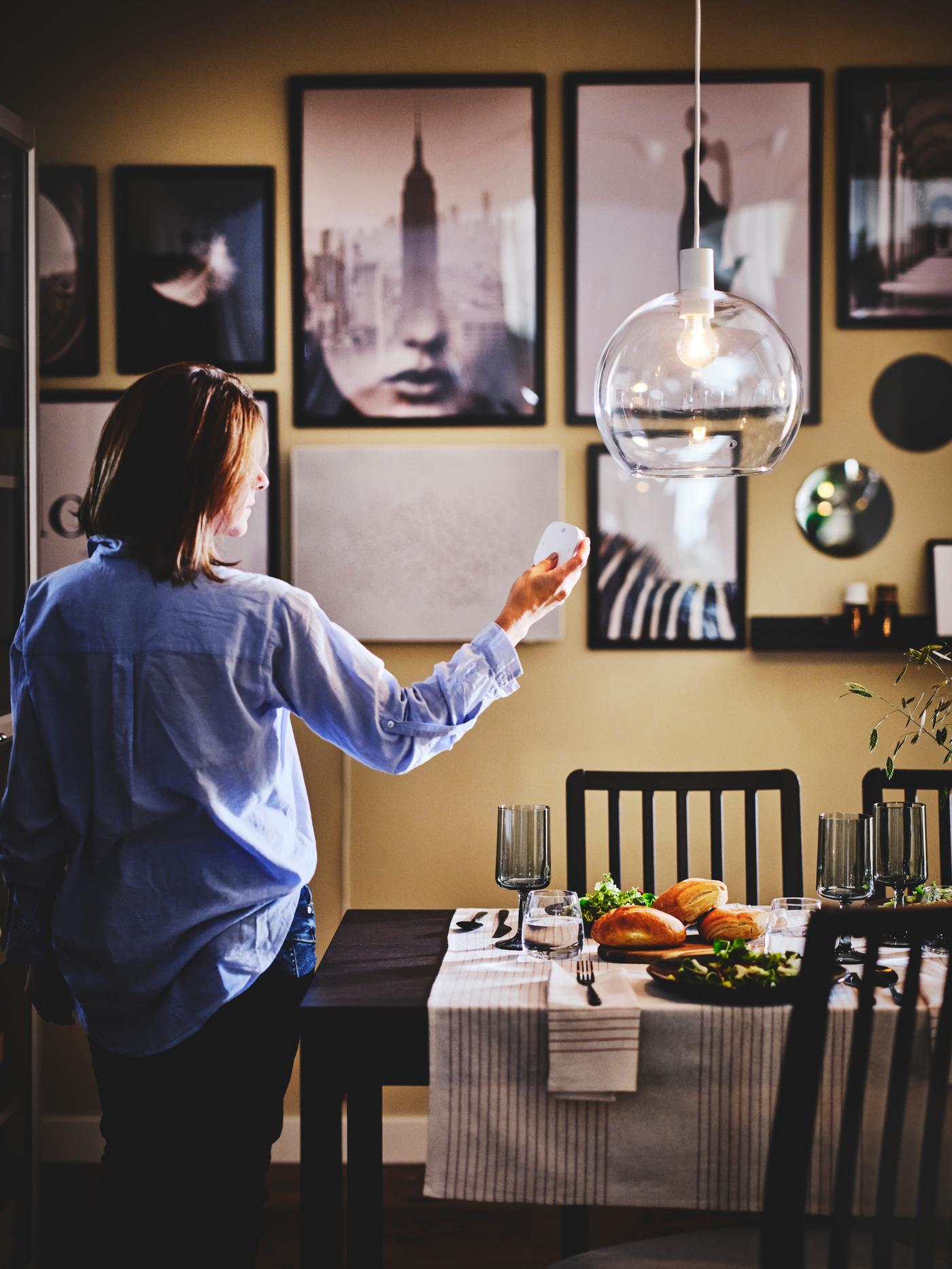 Woman by the dining table installing the bulb in the chandelier