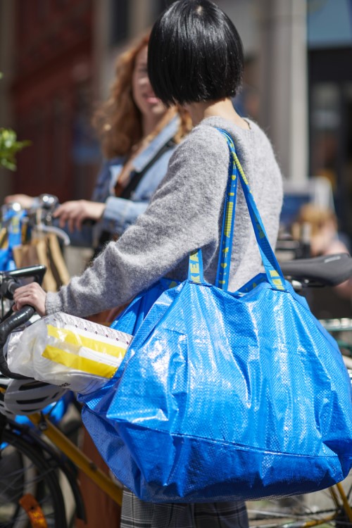Woman carrying FRAKTA bag full of items from IKEA