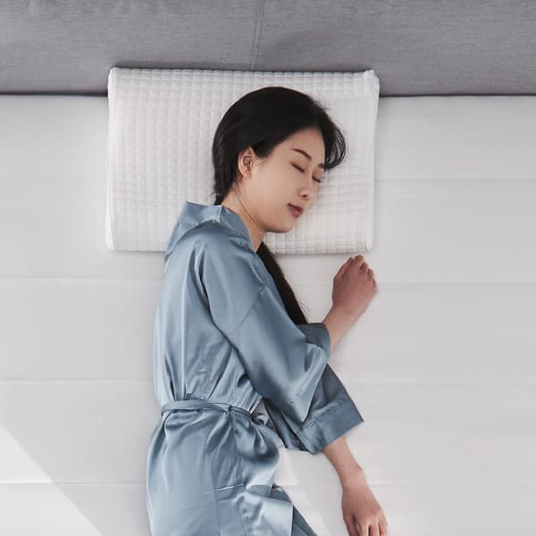 Woman lying on cooling KLUBBSPORRE pillow and mattress