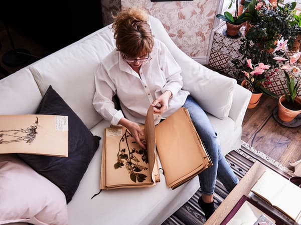Woman reading and sitting on a FÄRLÖV white sofa.