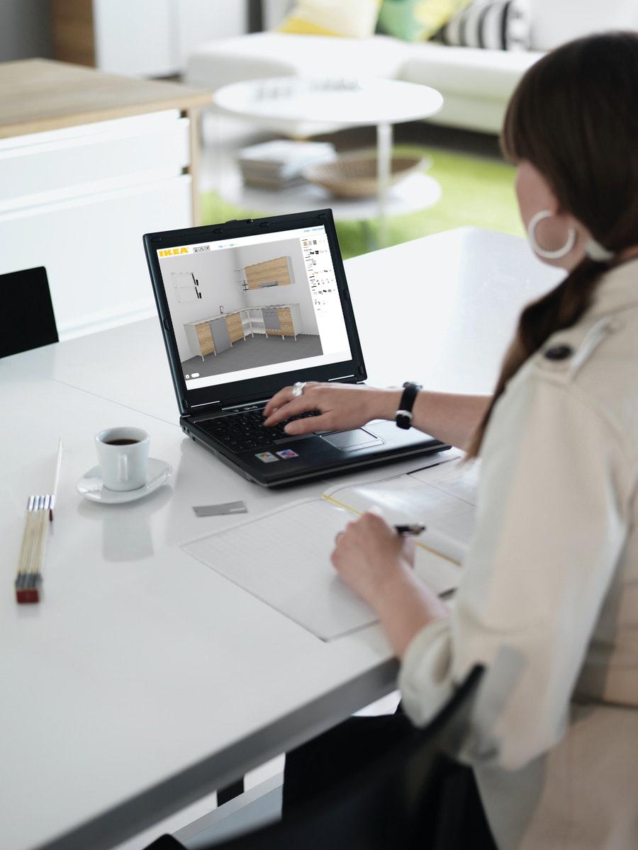 Woman sitting at a white desk working on a laptop computer