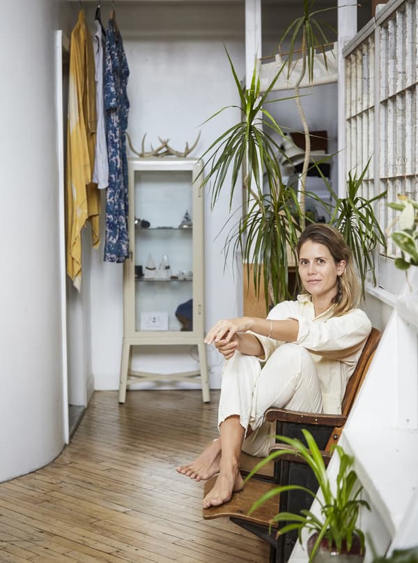 Woman sitting on a chair in a room with plants.