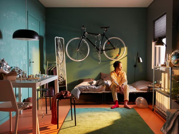 Woman sitting on a HAMMERN sofa bed.