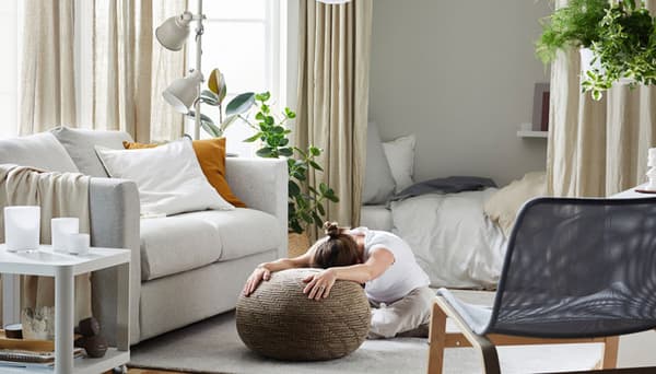 Woman stretching while sitting on SANDARED pouffe, beige