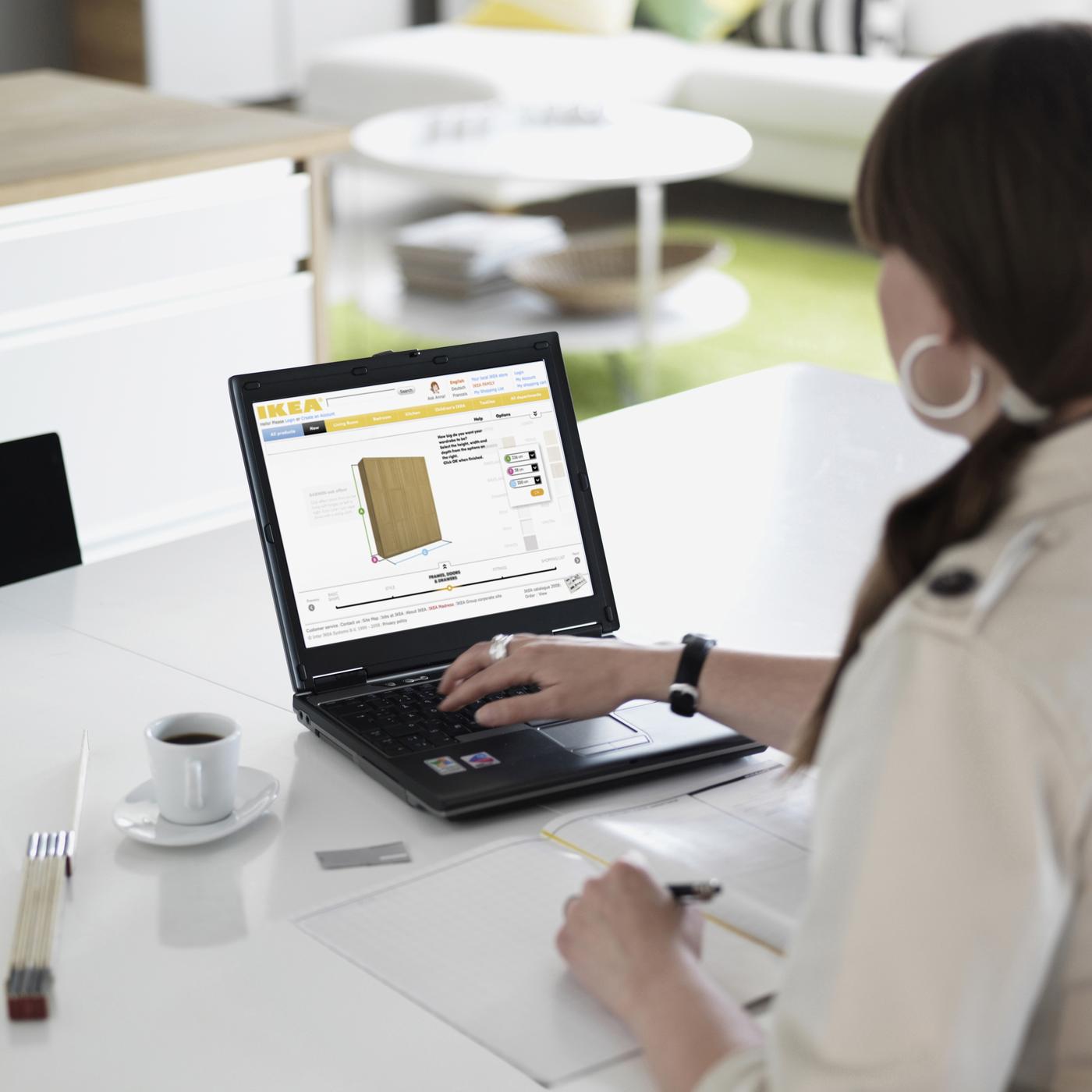 Woman working on laptop on white desk, using online planning tool