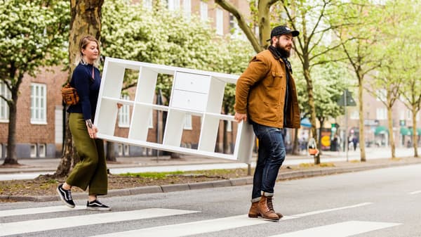 Women and man crossing a street carrying a bookcase